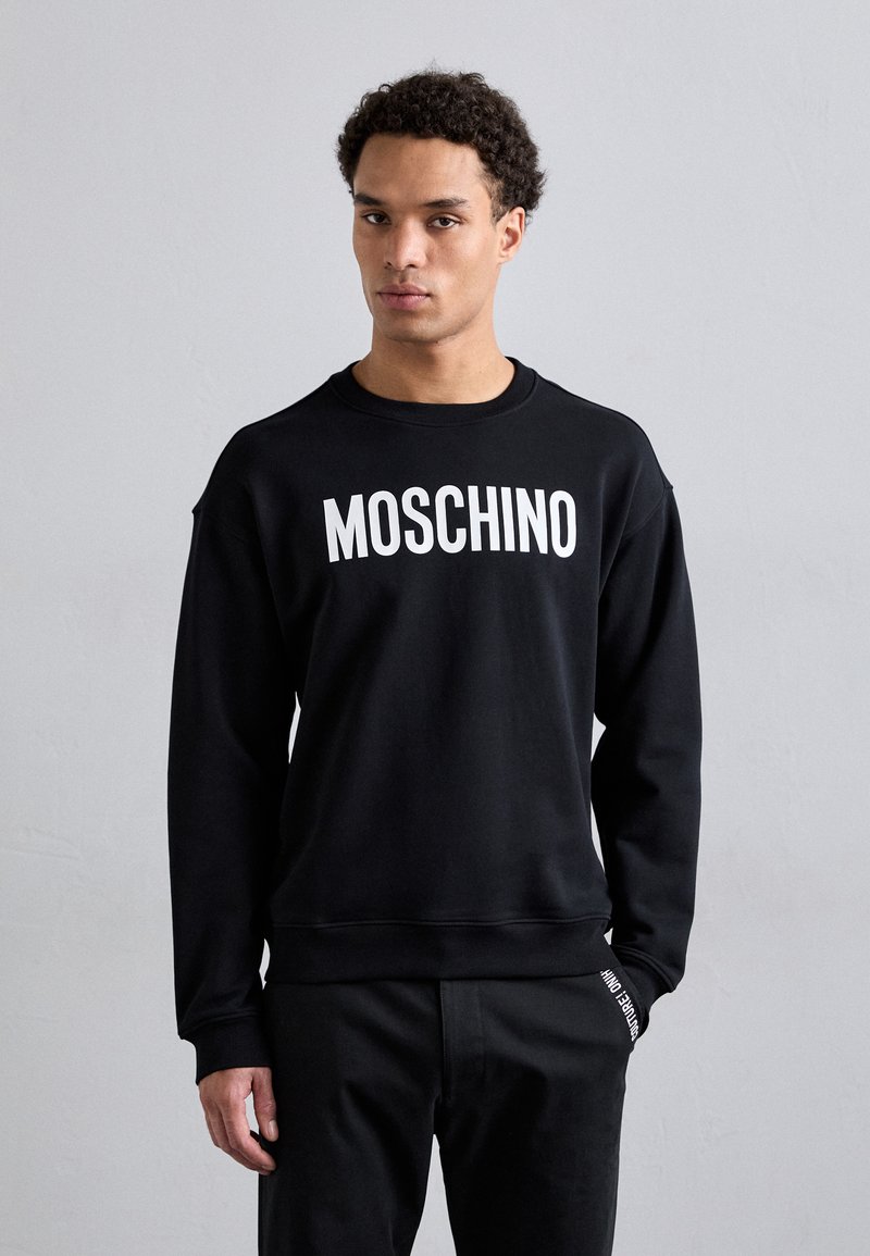 Schwarzer Sweatshirt aus Baumwolle mit Rundhalsausschnitt, der mit fettgedrucktem weißen "MOSCHINO"-Text über die Brust versehen ist, langen Ärmeln und gerippten Bündchen.