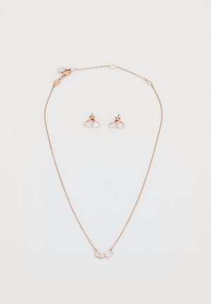 La collana in oro rosa e gli orecchini abbinati presentano accenti di cristallo. La collana ha una complessa catena con un pendente di gemma; gli orecchini sono in stile a bottone.