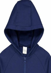 Felpa zip con cappuccio di colore blu navy, realizzata in morbido tessuto di cotone, con dettagli di cucitura e un'etichetta all'interno dell'area del colletto.