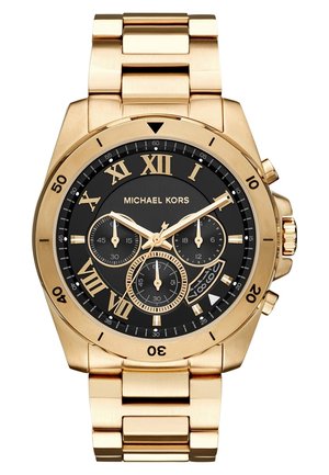 Goldfarbene Michael Kors Armbanduhr mit schwarzem Zifferblatt, römischen Zahlen, drei Hilfszifferblättern, Datumsfenster und Gliederarmband aus Metall.