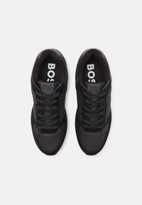 Zapatillas negras con una combinación de materiales de tela y ante. Presentan una puntera redondeada, diseño con cordones y la marca "BOSS" en la plantilla.
