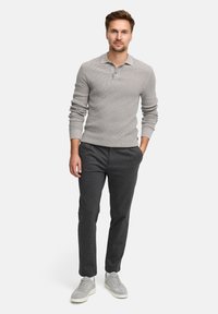Polo a maniche lunghe grigio chiaro in maglia con colletto, abbinato a pantaloni aderenti grigio scuro e sneakers grigie.