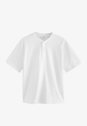 Fehér, rövid ujjú póló, kerek nyakkivágással és három gombos panelekkel. Simább, könnyű pamut anyagból készült.