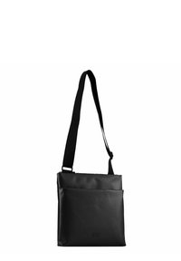 Bolso negro de hombro hecho de material impermeable, con un diseño plano, correa ajustable y un bolsillo frontal con un logo grabado sutil.