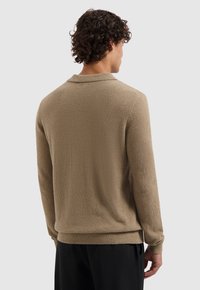 Bruine textuurtrui met een kraag, lange mouwen en een geribde zoom. De stof ziet er zacht uit en heeft een casual, ontspannen pasvorm.