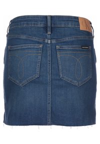 Jeanskjol i mörkblå färg, fransad nederkant, två bakfickor och Calvin Klein-logotyp nära midjan. Diskreta sömnadsdetaljer.