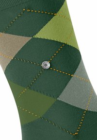 Zielone skarpetki w argyle z teksturowanym materiałem, diamentowym wzorem w różnych odcieniach zieleni i szarości, z pomarańczowym haftem i srebrnym akcentem logo.