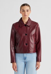 Burgunderrote Lederjacke mit Kragen, ausgestattet mit schwarzen Knöpfen, zwei Fronttaschen und einem taillierten Schnitt. Glatte Textur.