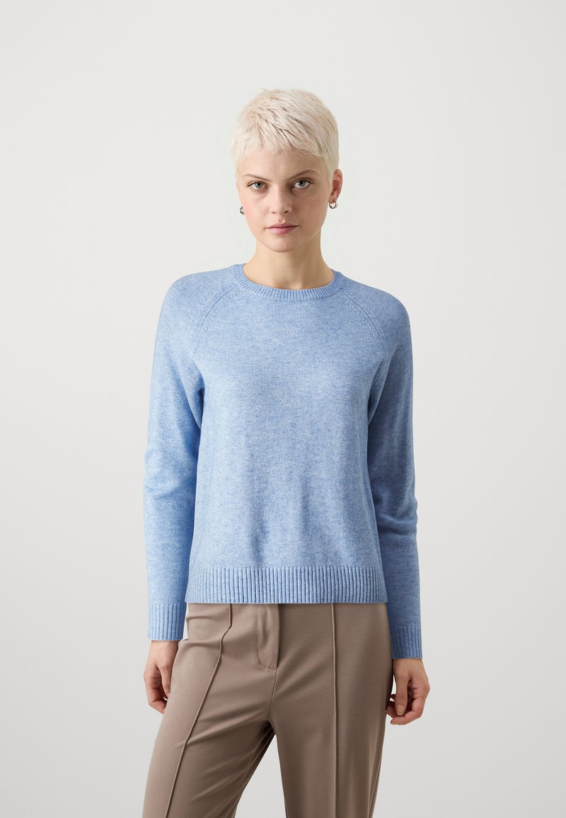 Pulover bleu deschis cu guler rotund, tiv zimțat și mâneci lungi, realizat dintr-un material moale și texturat. Asortat cu pantaloni neutrali.