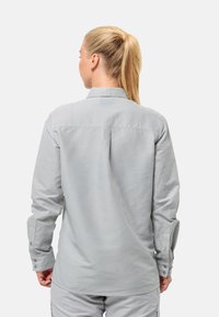 Helles graues Langarmhemd mit Kragen, Knopfmanschetten und einem lässigen Schnitt. Weiche Textur und Rückenpasse sichtbar.