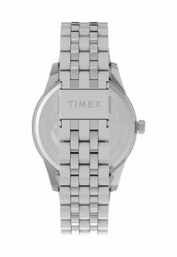 Reloj de acero inoxidable plateado con pulsera de eslabones texturizados, que presenta una caja redonda y una corona en el lateral, estampada con "TIMEX."