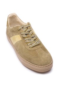 Tkanina patike od brušene kože u bež boji s glatkim žutim kožnim prugama. Ima teksturirane, višebojne pertle i gumenim potplatom. Dizajn s okruglim vrhom.