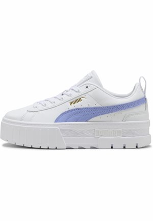 Zapatilla blanca Puma con plataforma y suela gruesa, línea lavanda a un lado, logo dorado de Puma cerca de los cordones y tira para tirar en el talón.