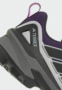 Purpurfarbupper aus Textil mit Netzeinsätzen, verstärkte graue Zwischensohle und dicke schwarze Gummisohle. Mit "TERREX"-Branding und einer Zuglasche.