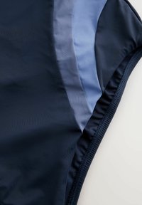 Marinefarbene Badebekleidung mit glatter Textur und hellblauen Einsätzen. Das Design umfasst elastische Nähte und eine enganliegende Form.