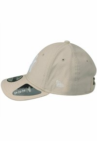Beige Baseballcap aus Netzstoff, mit gebogenem Schirm, aufgesticktem Logo in Weiß und angebrachten Etiketten. Verfügt über eine strukturierte Form und Belüftungsöffnungen.