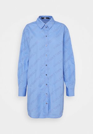 Chemise bleu clair avec un col boutonné, des manches longues et un motif textuel répété de "Karl Lagerfeld" sur le tissu.