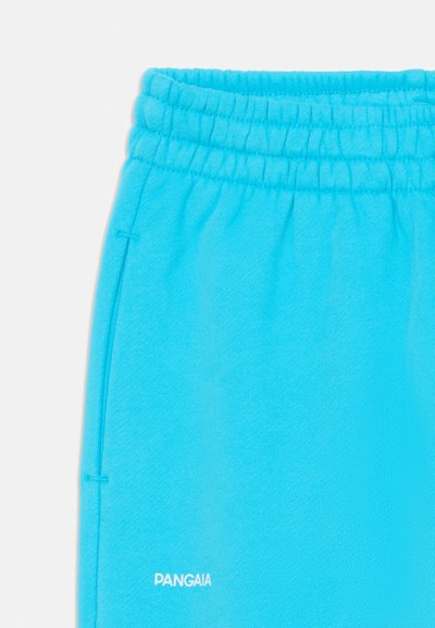 Pantalones jogger color turquesa hechos de un tejido suave, con una cintura elástica y un pequeño logo blanco en la parte inferior izquierda.