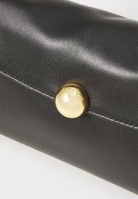 Pochette en cuir noir au fini lisse, avec une fermeture à bouton doré gravée "Furla" et des détails de couture soignés.