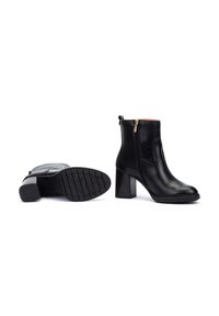 Botas de cuero negras hasta el tobillo con un tacón alto en bloque, cremallera lateral, textura suave y suela de goma con patrón para mayor tracción.