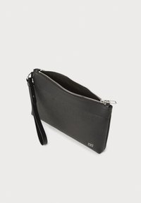 Pochette noire en cuir texturé, avec des accents lisses, fermeture éclair sur le dessus et une bandoulière amovible. Design rectangulaire compact, avec un branding minimal.