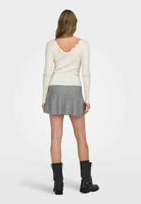 Biała, prążkowana bluzka z długim rękawem i falbanastym tyłem, szara spódnica w dzwony oraz czarne, sięgające kolan botki z klamrami. Gładkie materiały, luźny styl.