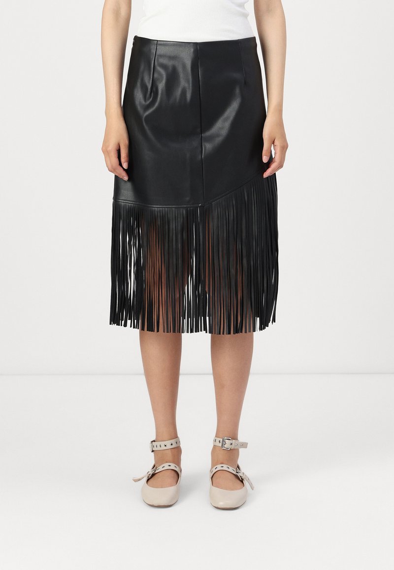 Fekete műbőr szoknya rojtos alsó széllel, testre simuló fazonnal és diszkrét varrási részletekkel. A modellen világos színű, pántos cipők vannak.