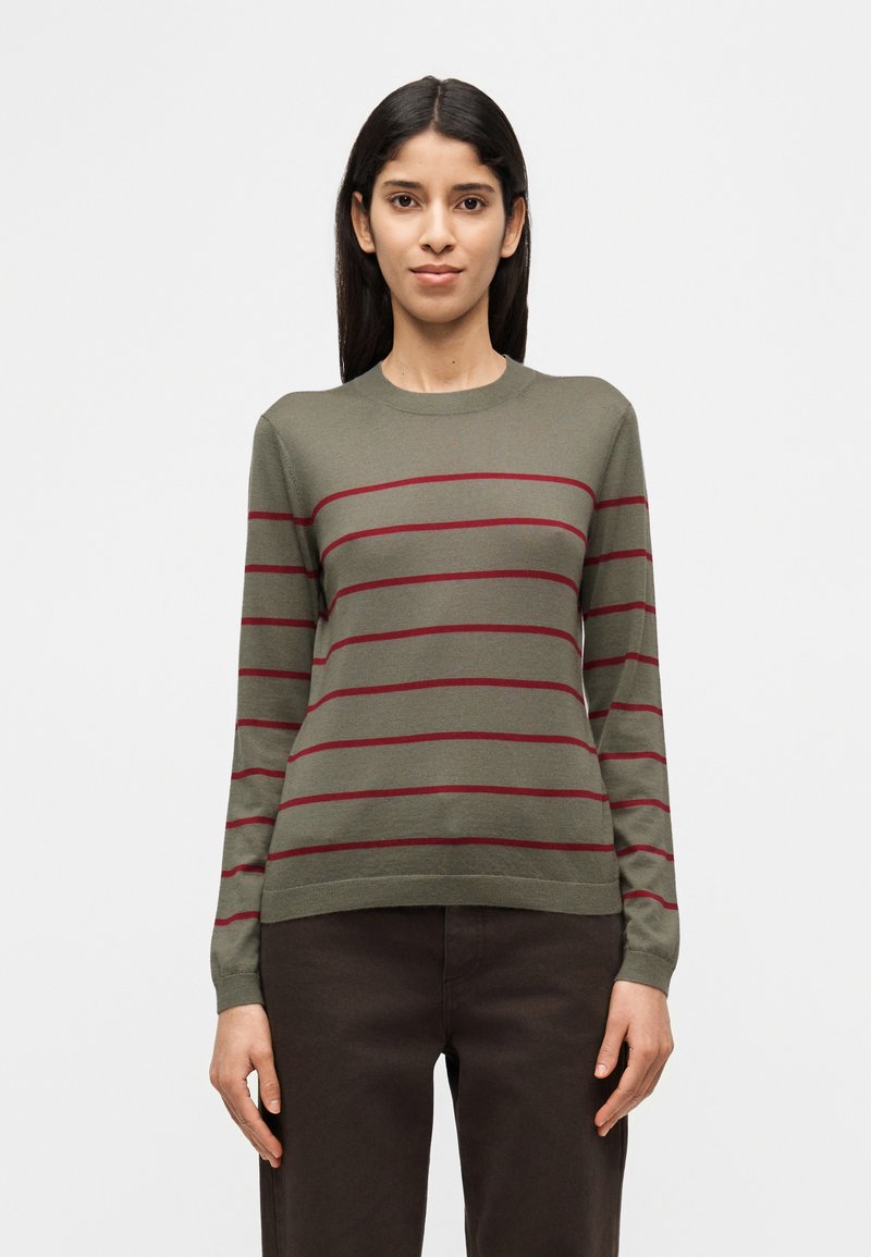 Πουλόβερ σε ελιά πράσινο χρώμα με οριζόντιες μαρονοκόκκινες ρίγες, στρογγυλή λαιμόκοψη, μακριά μανίκια και εφαρμοστή ραφή στη μέση. Μαλακή υφή υφάσματος, απλός σχεδιασμός.