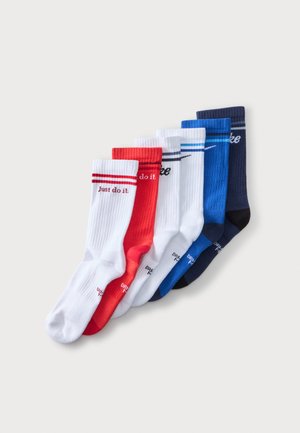 Έξι ζευγάρια κάλτσες Nike σε λευκό, κόκκινο, μπλε και ναυτικό, με τα λογότυπα "Just do it." και swoosh, τοποθετημένα σε σχήμα βεντάλιας σε απλό φόντο.
