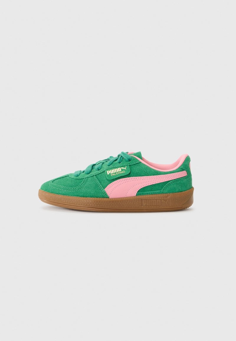 Baskets Puma en daim vert avec bande rose et semelle en gomme, vue de côté sur fond gris clair uni.