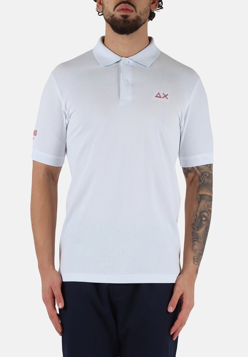 Polo bianco realizzato in misto cotone, con colletto classico, maniche corte e un logo rosso chiaro sul petto e sulla manica.
