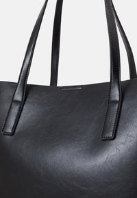 Sac fourre-tout noir en simili cuir texturé, doté de deux poignées robustes et d'un design sans coutures avec un matériel minimal.