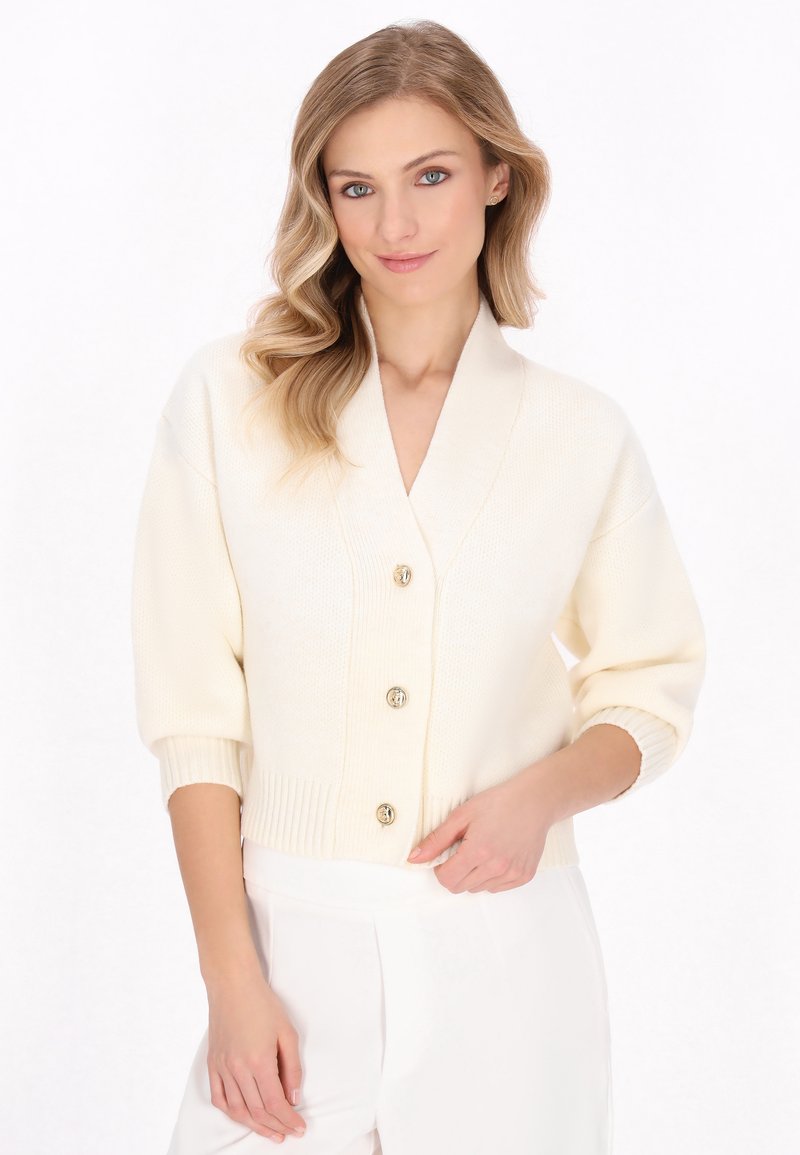 Cardigan crema con scollatura a V, maniche corte, orlo a coste e cinque bottoni dorati. Il tessuto a maglia texturizzato offre un aspetto accogliente.