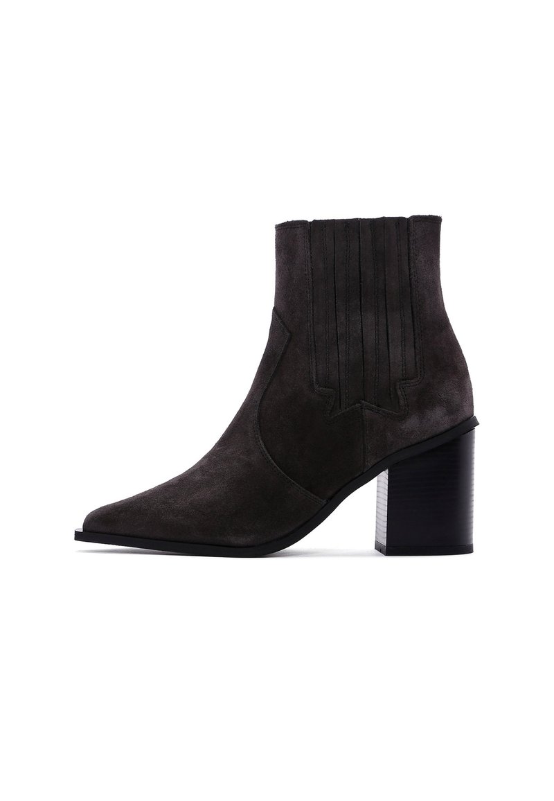 Bottines en daim gris foncé avec un bout pointu et des accents de coutures verticales. Le talon noir épais ajoute de la stabilité et contraste avec la texture douce.