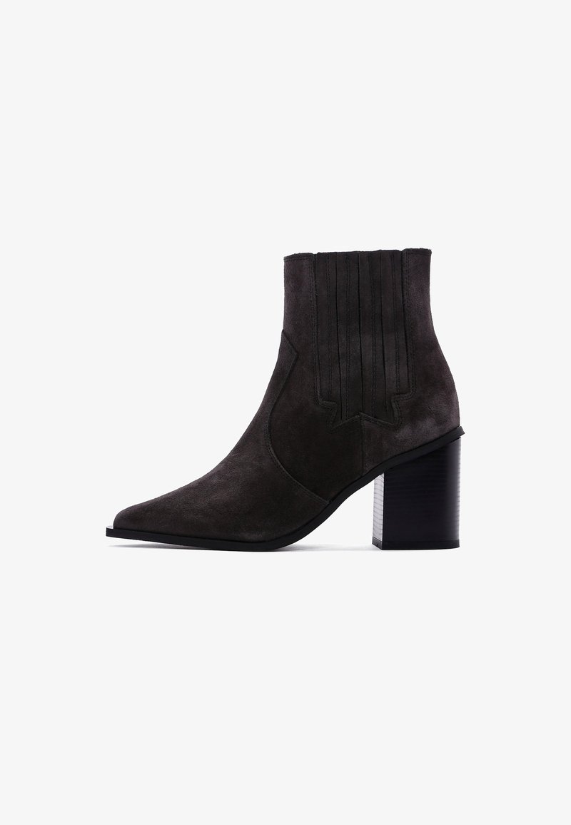 Bottines en daim gris foncé avec un bout pointu et des accents de coutures verticales. Le talon noir épais ajoute de la stabilité et contraste avec la texture douce.