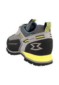 Scarpa da trekking grigia e nera con accenti gialli, materiali in suede e gomma, suola robusta, tallone rinforzato e design traspirante.