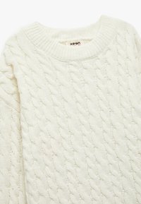 Witte gebreide trui met een kabelbreipatroon, ronde halslijn en gestructureerde stof. Etiket zichtbaar binnenin de kraag.