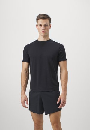 Svart t-skjorte med korte ermer laget av mykt stoff, med rund hals og slim fit. Modell iført matchende svart shorts.