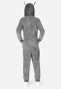 Sivý fleecový overal s kapucňou, na ktorej sú zvieracie uši, rebrované manžety v odtieňoch teal a čiernej, a voľný strih. Mäkká textúra po celom obvode.