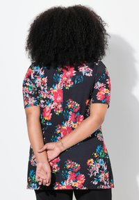 Bloemdruk tuniek met korte mouwen, zwarte achtergrond, levendige roze, rode en groene bloemen, zachte stof, ontspannen pasvorm, gebogen zoom.