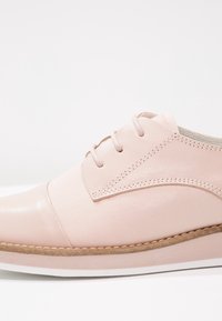 Scarpa lacci rosa chiaro con punta in pelle liscia e tomaia in tela. Presenta cuciture tonali e una suola in gomma con bordo texturizzato.