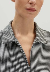 Zwart-witte gestreepte overhemd met kraag en een diepe V-hals. De stof lijkt een textuur te hebben met een geometrisch ontwerp.