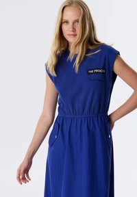 Bla dresses mit kurzen Ärmeln, elastischem Bund, zwei Seitentaschen und einem Logo-Detail auf der Brust. Glatte Stoffqualität mit fließendem Design.