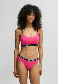 Fuchsia bralette och matchande shorts i stretchmaterial, med svart logoband i midjan och justerbara band på toppen.