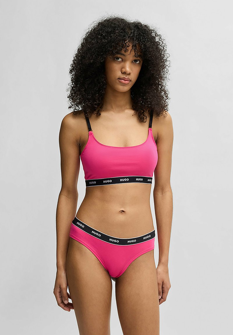 Fuchsia bralette och matchande shorts i stretchmaterial, med svart logoband i midjan och justerbara band på toppen.