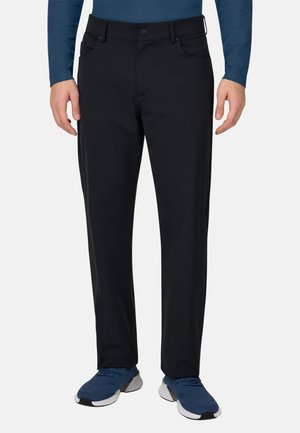 Schwarze Hosen mit geradem Bein, aus weichem Stoff, mit vorderen Taschen und einem Knopfverschluss, kombiniert mit blauen Sportschuhen.