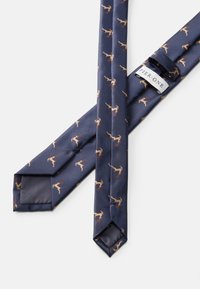 Γαλάζια γραβάτα με υφή που φέρει επαναλαμβανόμενα λευκά σχέδια από ελάφια σε ανοιχτό καφέ, συμπεριλαμβανομένων των κέρατων, και μια μικρή ετικέτα μάρκας.