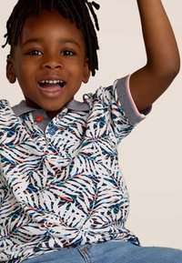 Poloshirt met korte mouwen, witte basis, kleurrijk bladpatroon en contrasterende blauwe kraag. Voorzien van twee knopen en textiel met een structuur.