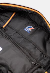 Interno nero di una borsa con un accento colorato a righe, multiple tasche e un etichetta con il logo K-Way. Il materiale appare liscio e resistente.