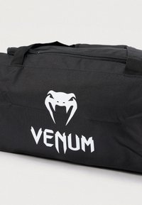 Geantă duffel neagră, cu logo și grafică albă VENUM; confecționată din material durabil, cu închidere cu fermoar și mânere robuste pentru transport.